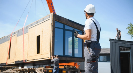 Construction site workers aiding the delivery of off-site timber panels 
